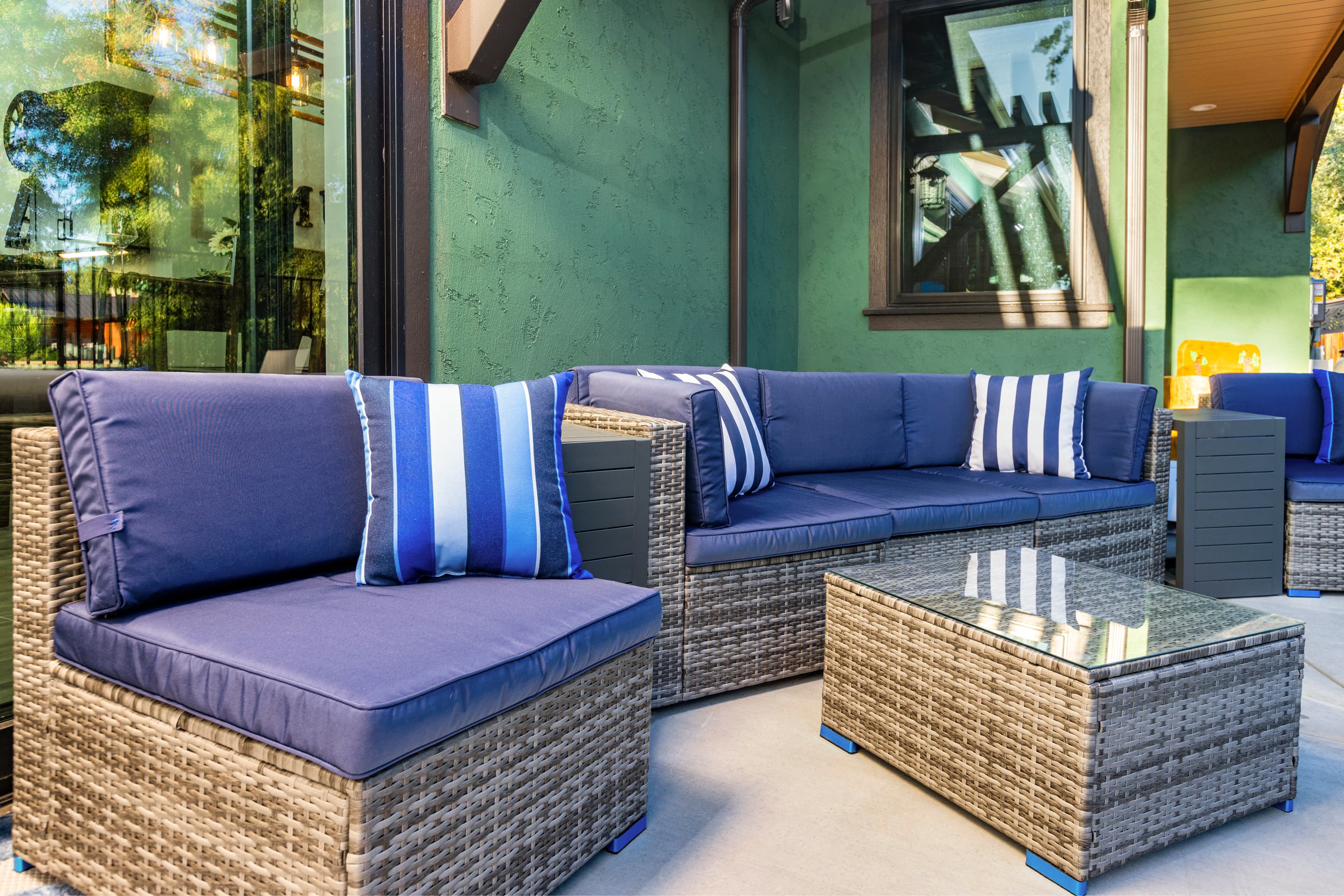 A cozy outdoor seating area featuring navy blue cushioned furniture and a glass-top coffee table.