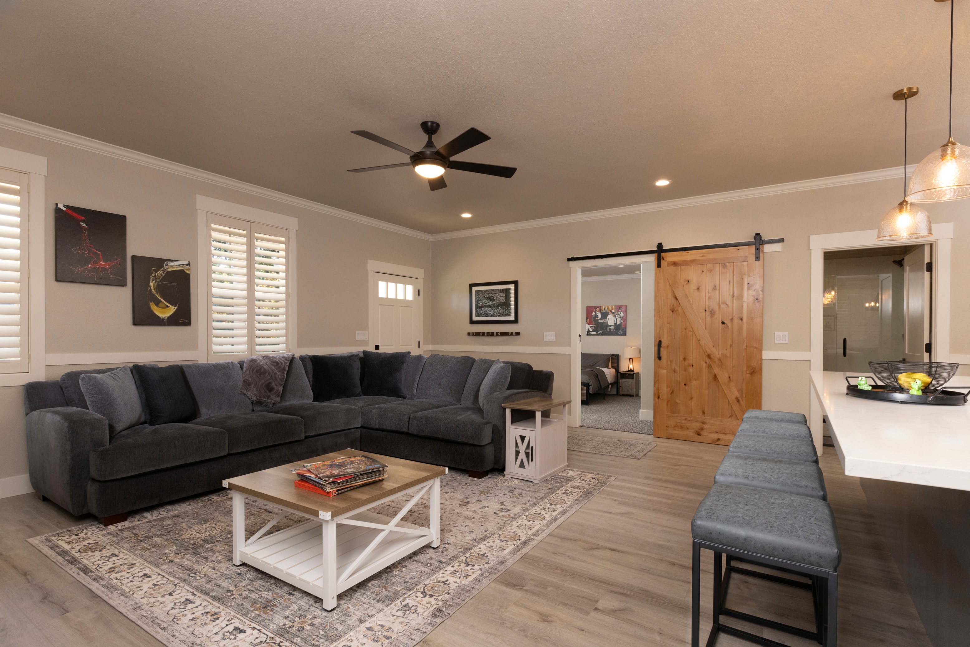 A cozy living room featuring a large gray sectional sofa, a white coffee table, and a sliding wooden door.