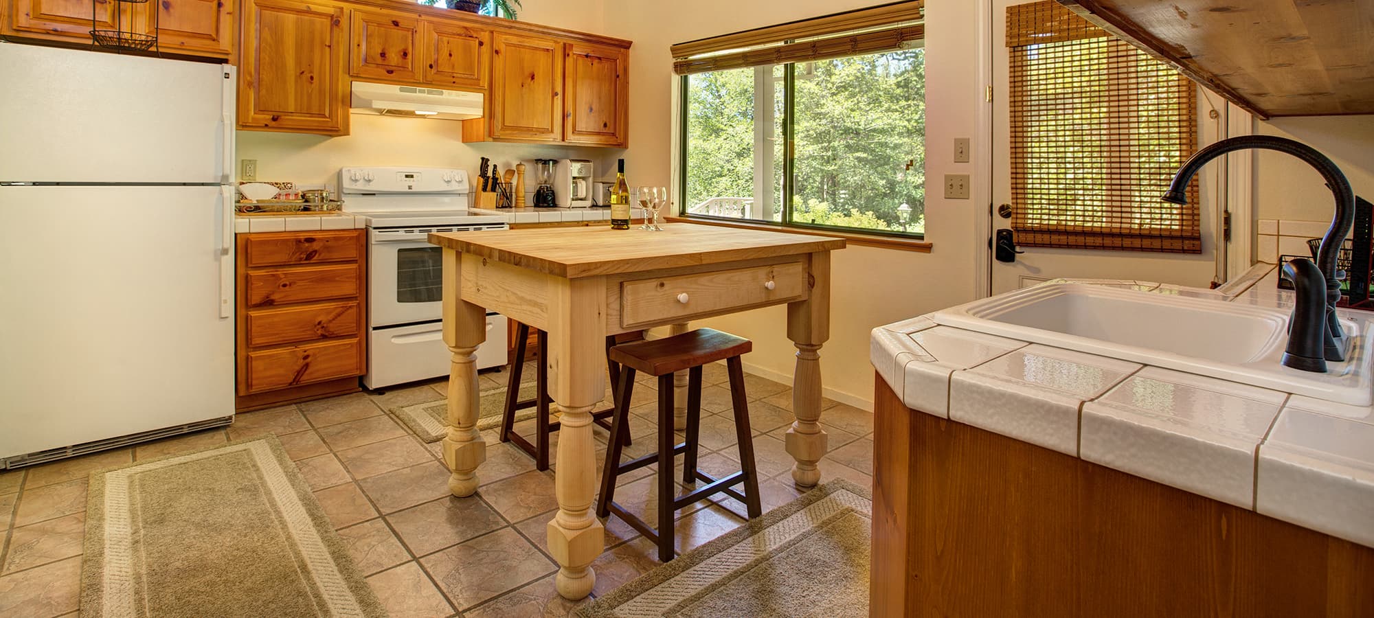 Cozy kitchen with wooden cabinets, a central island, and large windows letting in natural light.