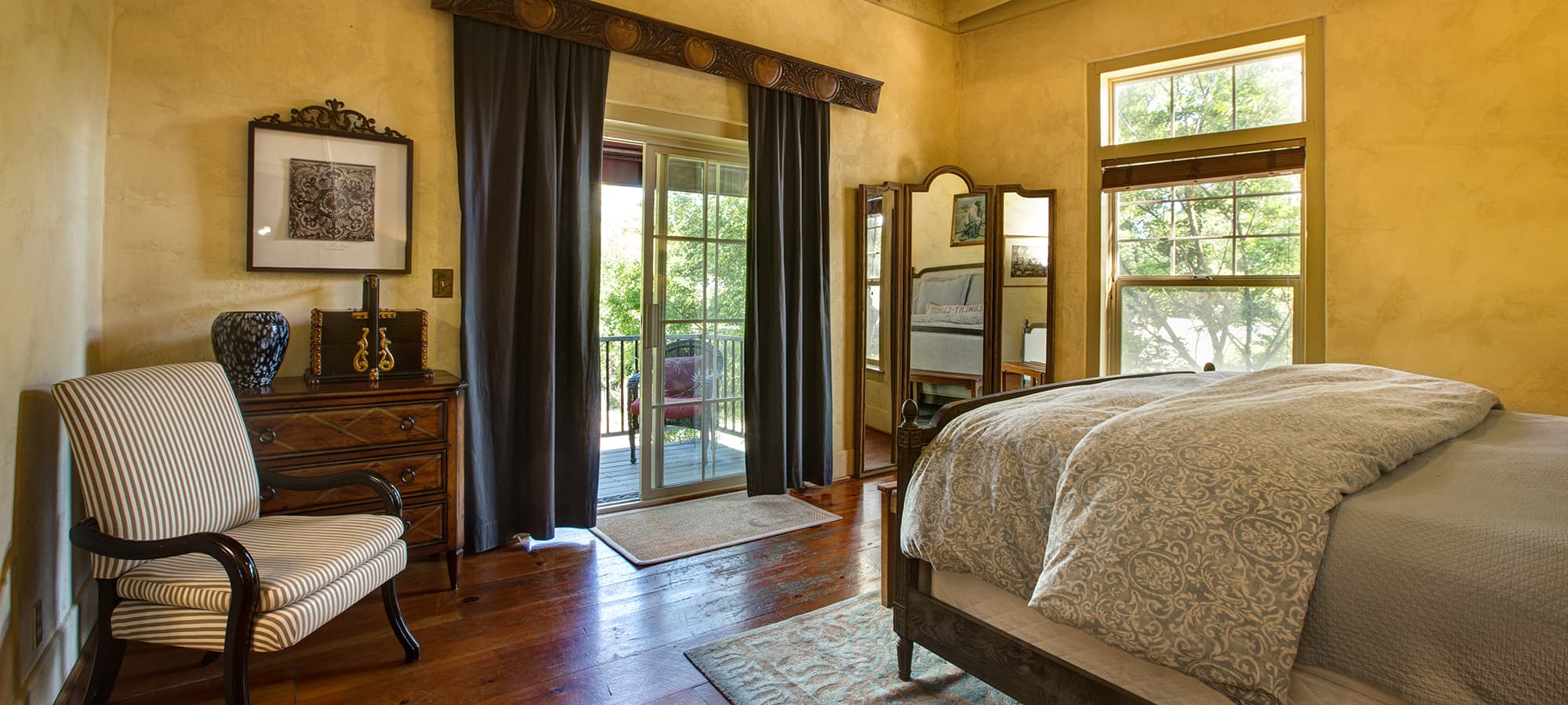 Bright bedroom with a large bed, an armchair, and sliding glass doors leading to a balcony.