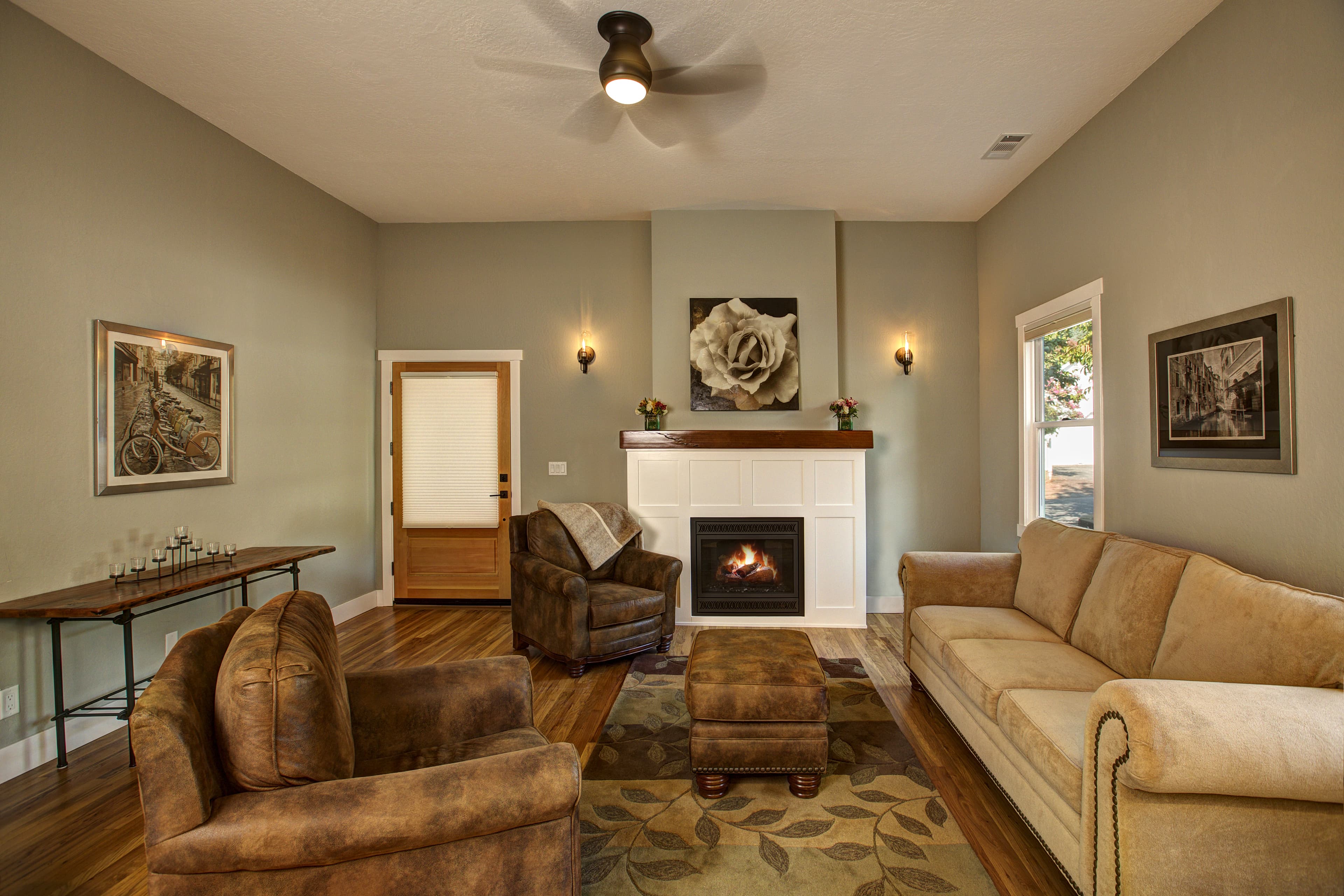 A cozy living room featuring brown seating, a fireplace, and decorative wall art.