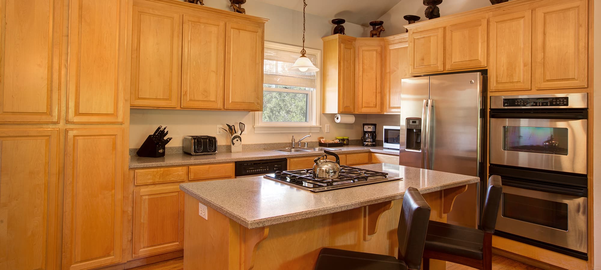 A modern kitchen with wooden cabinets, stainless steel appliances, and a central island with a stovetop.