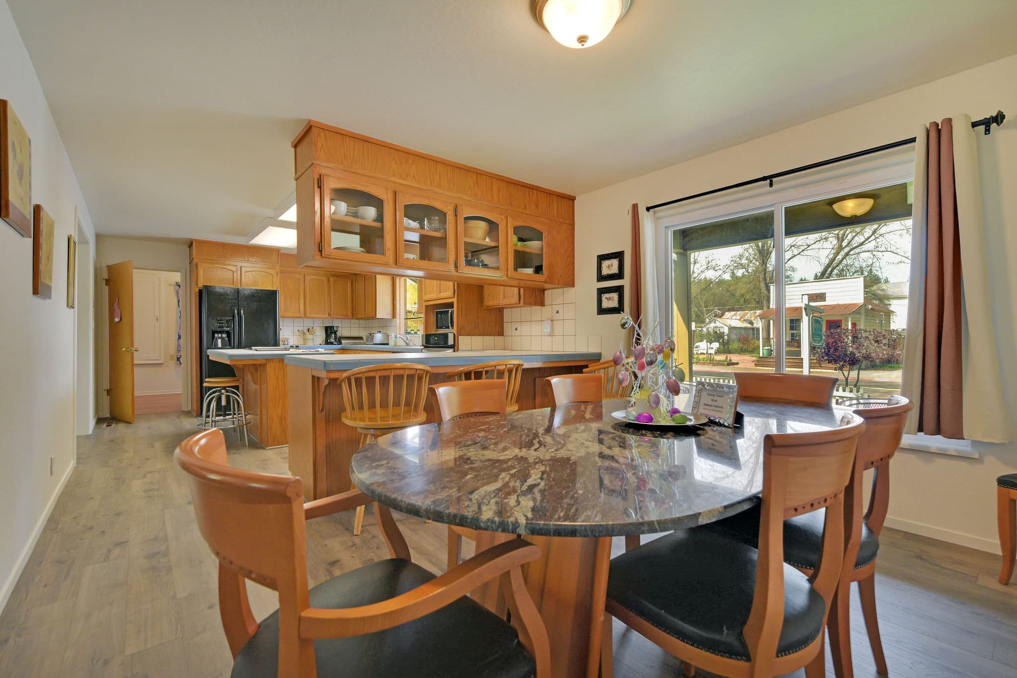 A modern kitchen with wooden cabinets and a round dining table set up beside a window.